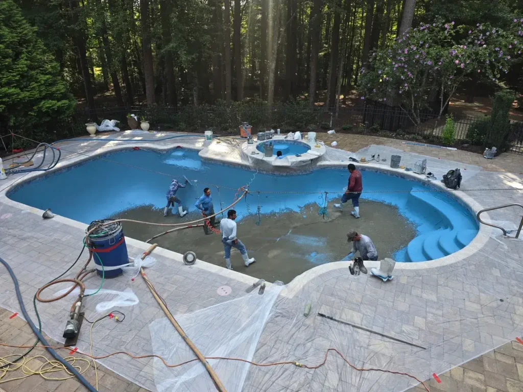 Crew applying a new blue interior finish to a pool in Atlanta, GA