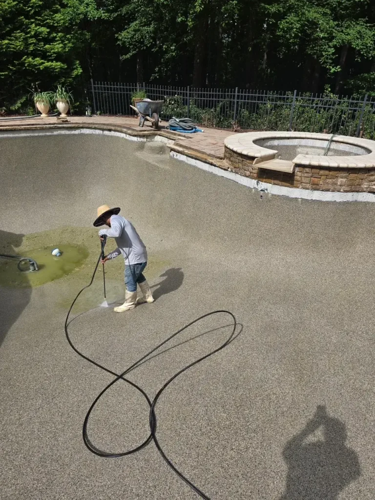 BluVantage technician pressure washing a drained pool during surface preparation